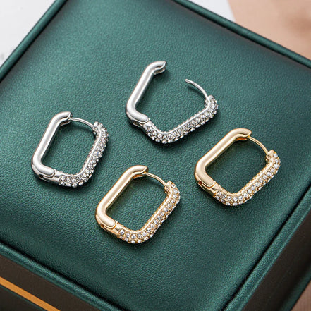 Square hoop earrings in gold and silver tones with sparkling crystals on green box